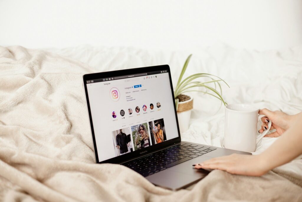 a woman is holding a coffee cup and looking at her laptop