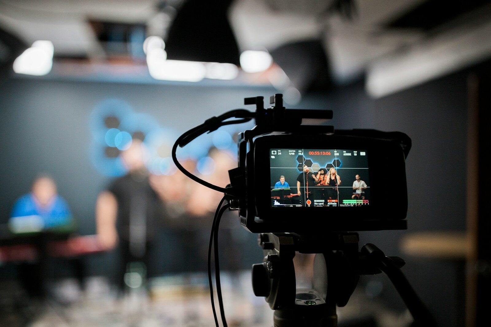 A professional video camera recording a musical group performing in a studio