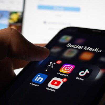 A person holding a smart phone with social media on the screen