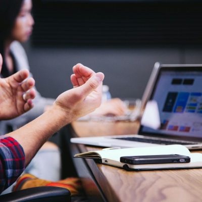 person gesturing during meeting with laptop