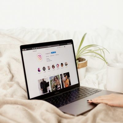 a woman is holding a coffee cup and looking at her laptop