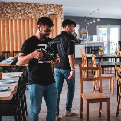 two men standing in a restaurant looking at a camera