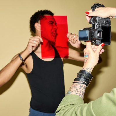 Man's face through red filter, being photographed by camera
